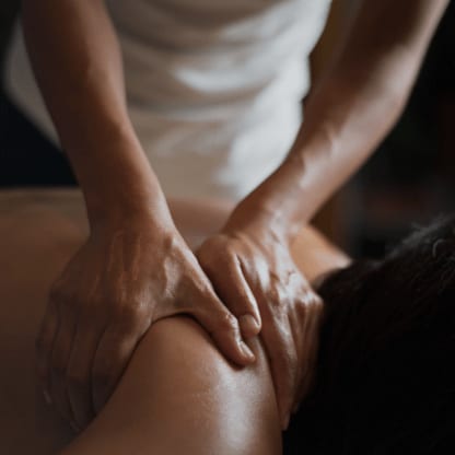 Massage von Nacken- und Schulterbereich in ruhiger, dunkler Atmosphäre