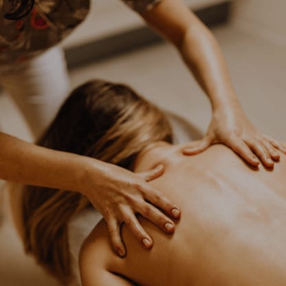 Rückenmassage einer Gästin im warmen Licht
