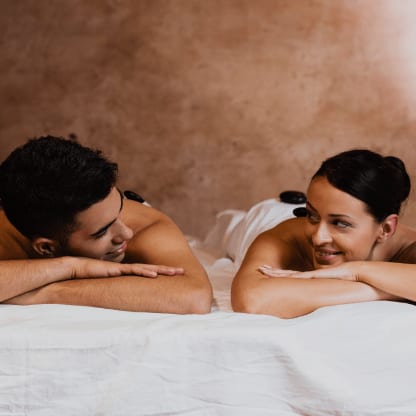 Ein Paar liegt sich lächelnd gegenüber, entspannt nach der gemeinsamen Massage